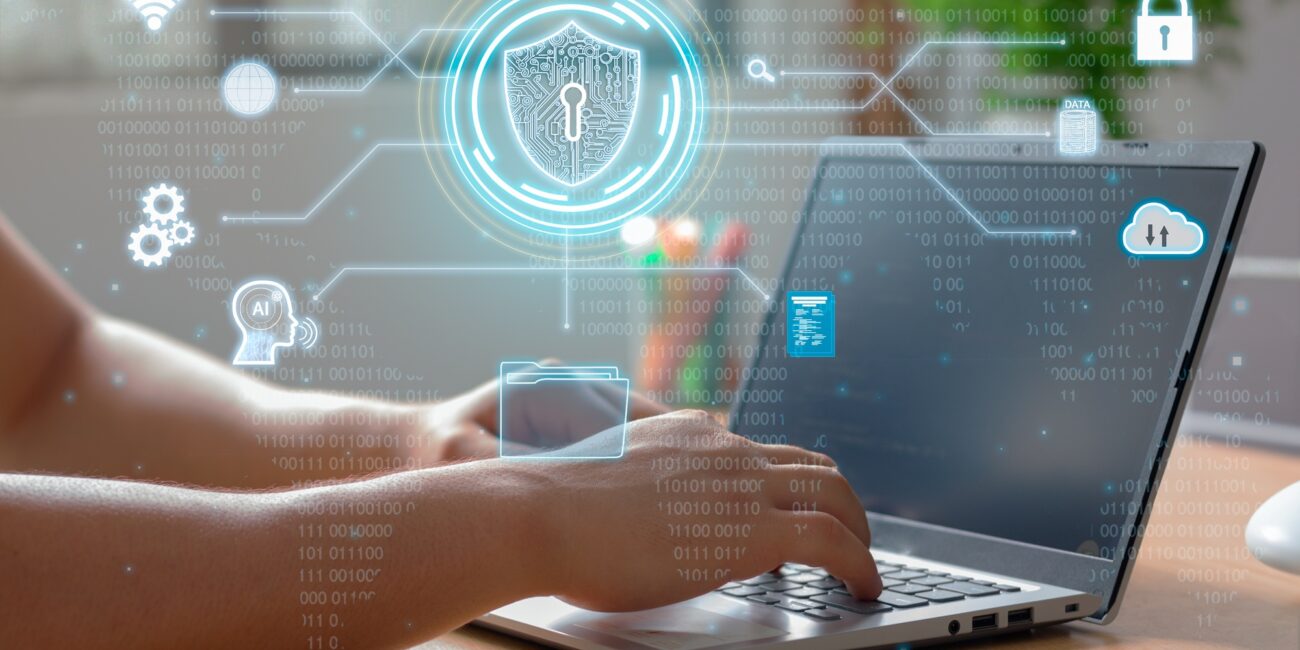 Mani che digitano su un laptop con sovrapposizione digitale di icone relative alla sicurezza dei dati, tra cui uno scudo con lucchetto e codici binari.