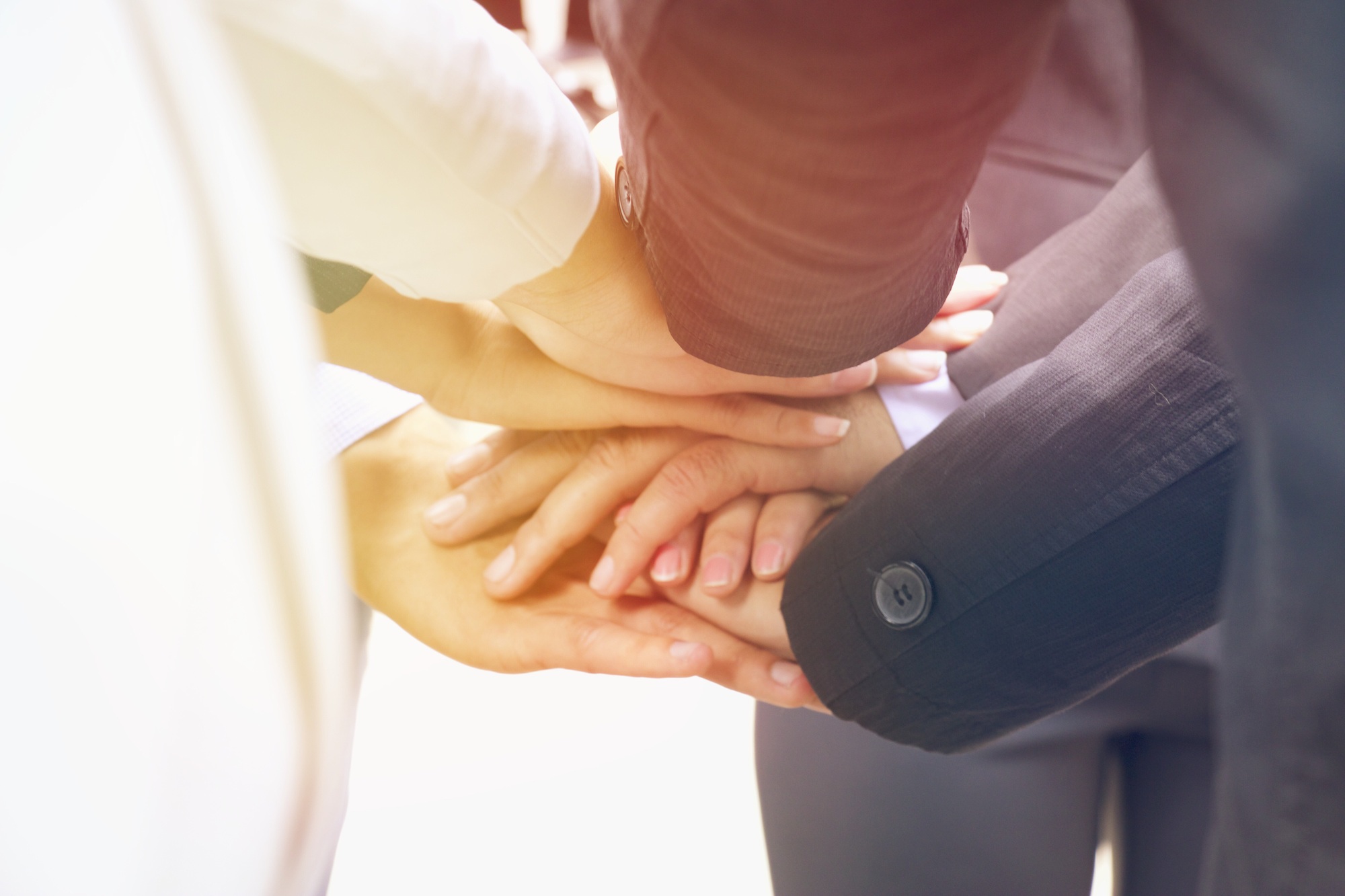 Gruppo di professionisti uniti in un gesto simbolico di collaborazione, con le mani sovrapposte in segno di squadra e fiducia.